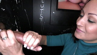 Busty brunette is sucking cock in a glory hole and gets a load