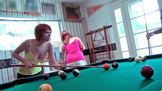 Redhead and brunette babes are playing pool in this video