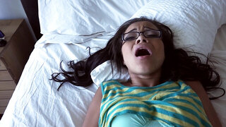 A hot thing with glasses is giving a blow job on the bed