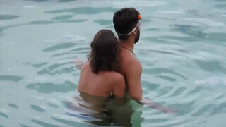 Nude babe caught jerking her BF's cock on the beach