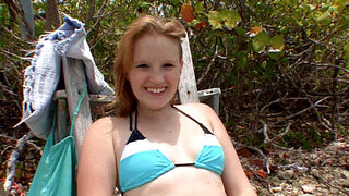 A smiling blue eyed honey is playing with a dick on the beach
